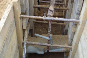 Sichern einer vorhandenen Rohrleitung im Holzbohlenverbau